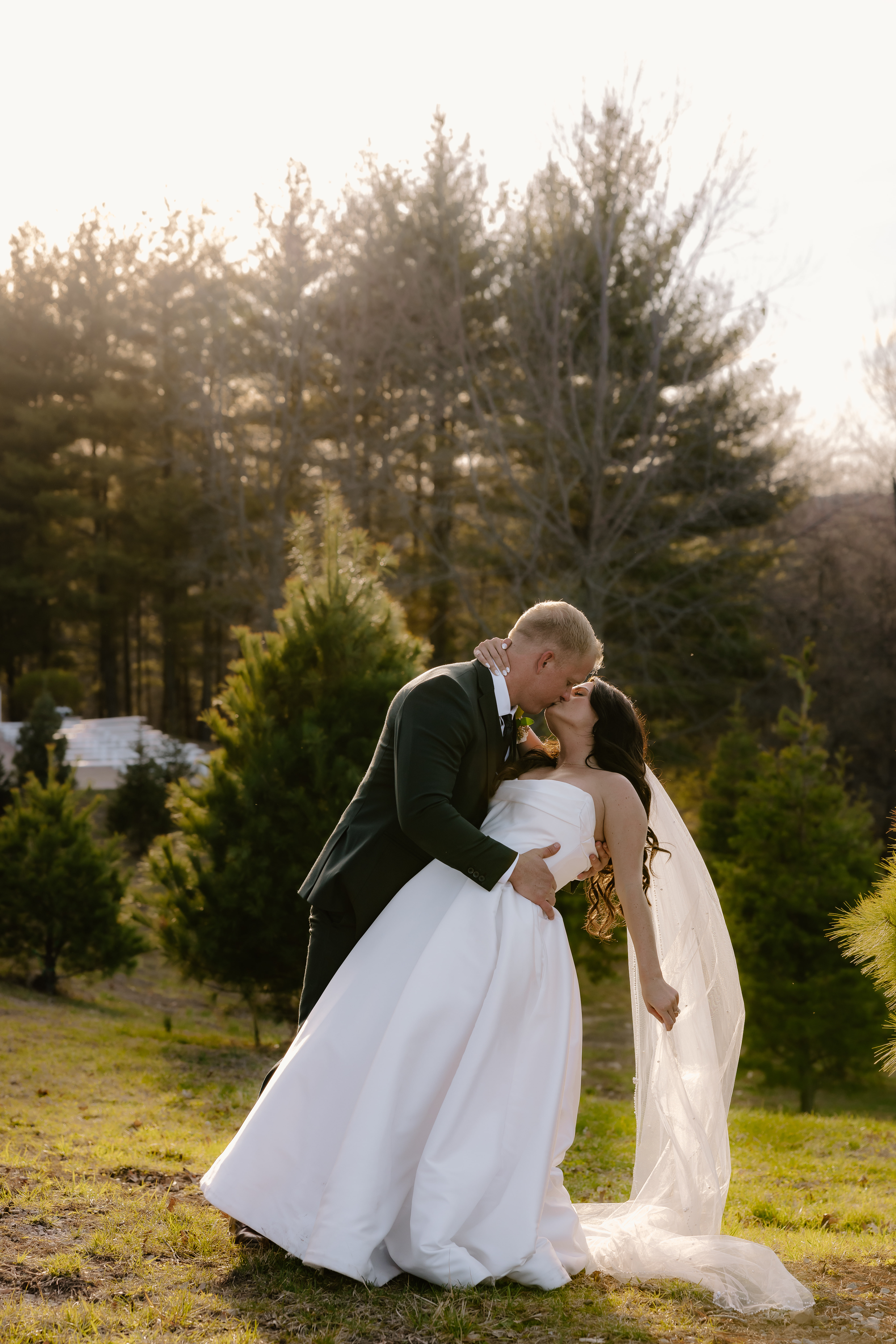 Bride and groom photographed in a kiss-dip during sunset on their wedding day, at the Fort Osage Christmas Tree Farm venue in Independence Missouri. Captured by destination wedding photographer, Samantha Mudd Photo.